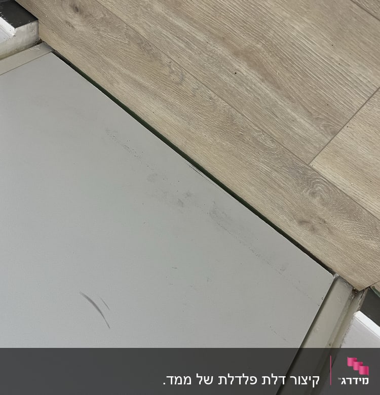 דלת מתכת עם ציר ליד רצפת עץ